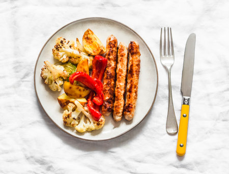 Chicken sausage and roasted vegetables on a light background, top viewの写真素材