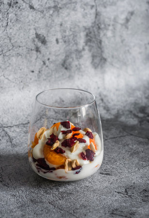 Natural greek yogurt with tangerine, dried cranberries and nuts on a gray background, top viewの写真素材