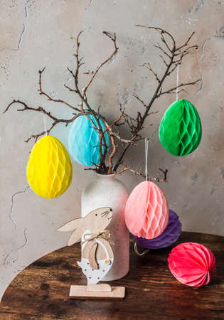 Easter still life - bouquet of tree branches with paper eggs and an easter wooden rabbit on the...