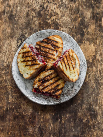 Hot sandwiches with cranberry jam and camembert on a wooden background, top viewの写真素材