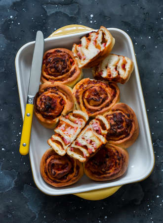 Pizza buns in a baking dish on a dark background, top viewの写真素材