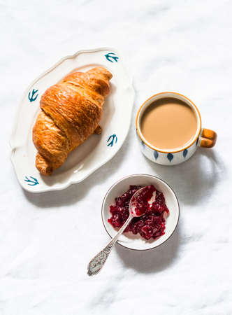 Croissant, coffee with cream, cranberry jam on a light background, top viewの写真素材