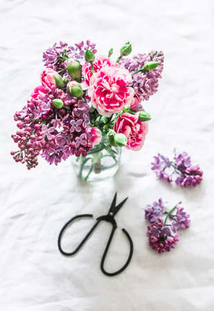 Bouquet of lilac and carnations, vintage scissors on a light background, top viewの写真素材