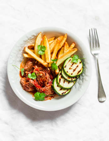 Slow cooker beef stew with grilled zucchini and french fries on a light background, top viewの写真素材