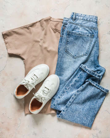 Women's casual walking wear - comfortable leather sneakers, beige t-shirt and blue jeans on a light background, top viewの写真素材