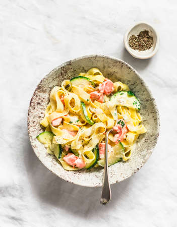 Fresh tagliatelle pasta with salmon and zucchini in cream sauce on a light background, top viewの写真素材