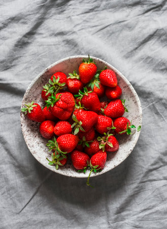 Fresh ripe strawberries in a bowl on a gray background, top viewの写真素材