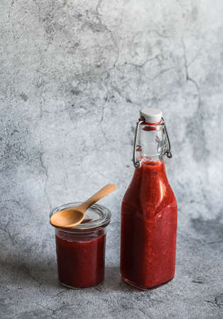 Rhubarb and strawberry sweet sauce in a canned bottle on a gray background. Free space for textの写真素材