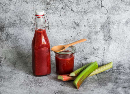 Rhubarb and strawberry sweet sauce in a canned bottle on a gray background. Free space for textの写真素材