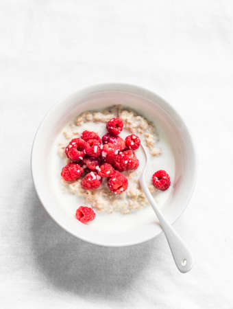Oatmeal porridge with fresh raspberries on a light background, top view. Delicious breakfastの写真素材