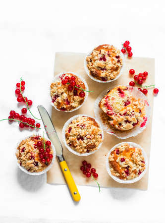 Red currant vanilla mini oatmeal cakes with sugar crumble on a light background, top view