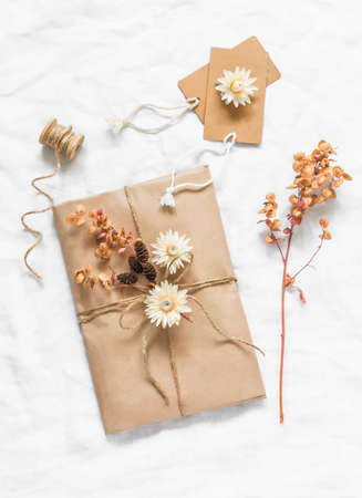 Creativity is a concept. Autumn gift packaging in craft paper with flowers, cones, twigs on a light...