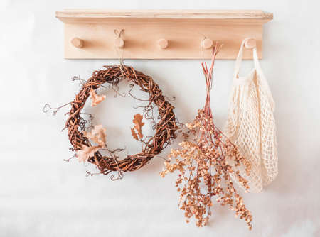 Autumn mood still life - wooden shelf with a vine wreath, dried flowers, fabric bag in a bright...