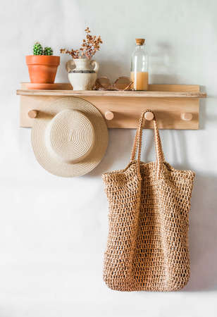 Straw shopping bag, hat on a wooden shelf in the hallway. Simple interior designの写真素材