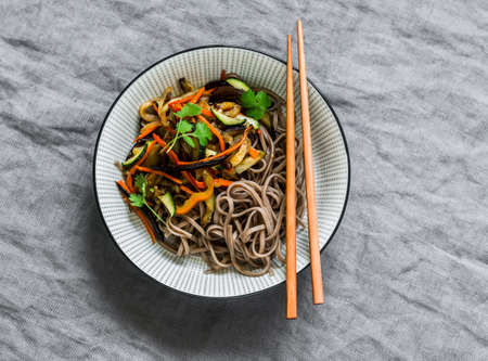 Vegetarian soba noodles with stir fry vegetables - delicious asian style lunch on a gray background,...