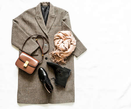 Women's autumn clothing - oversized plaid coat, leather black boots, leather bag, beige cashmere scarf on a light background, top view. Copy spaceの写真素材