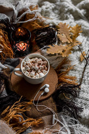 Cocoa with marshmallows, a cozy blanket, headphones on the bed. Autumn home cozy still life, top viewの写真素材