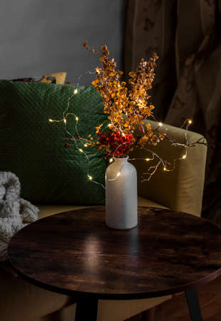 Cozy autumn evening interior of the room - yellow armchair with a green cushion, wooden table with a...