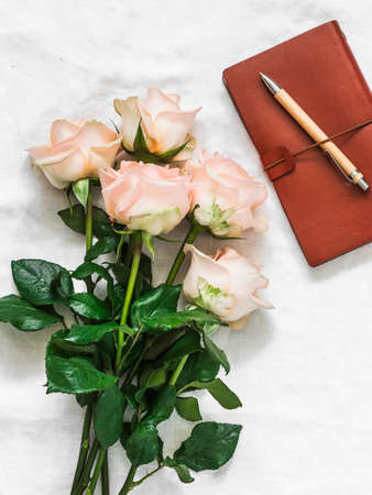 Bouquet of roses, leather planner and pen on the bed on a light background, top viewの写真素材