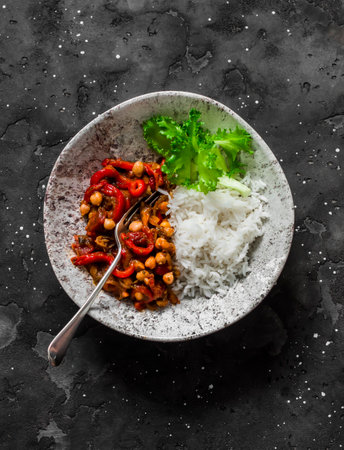 Vegetarian lunch - rice and eggplant, peppers, tomatoes sauce, chickpeas stew on a dark background, top viewの写真素材