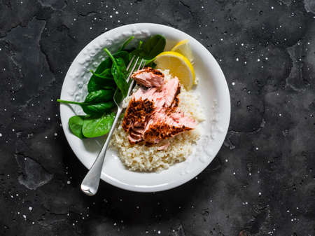 Healthy mediterranean lunch - lemon couscous, grilled salmon and fresh spinach on a dark background, top viewの写真素材