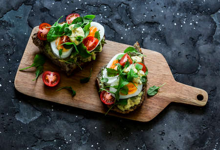 Vegetarian sandwiches with grain bread, avocado, boiled egg, micro-greens, cherry tomatoes and...