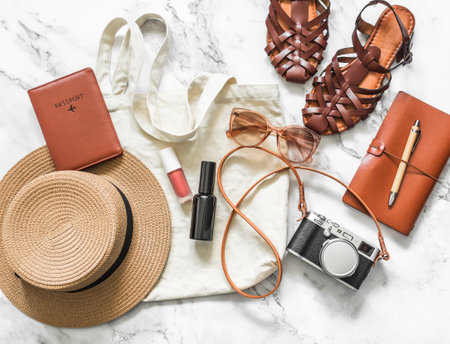 Women's travel accessories - textile shopper, hat, camera, passport, sunglasses, comfortable sandals on a light background, top viewの写真素材