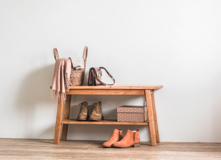 Scandinavian style interior. Wooden bench with shoes, a basket with a scarf, a warm blanket - an autumn homely atmosphere in the rustic style hallway roomの写真素材