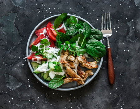 Souvlaki turkey, fresh vegetables salad on a dark background, top viewの写真素材