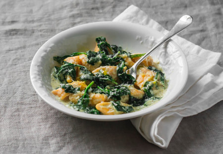 Pumpkin gnocchi with spinach cream sauce on a gray background, top view. Delicious lunchの写真素材
