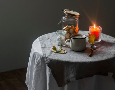 Cozy morning - a cup of coffee, butter cookies, a lit candle on the tableの写真素材
