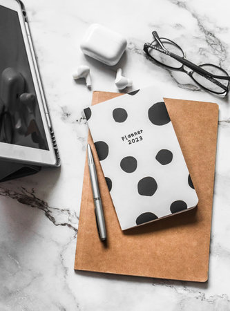 Planner 2023, organizer, tablet, headphones on a light marble background, top view