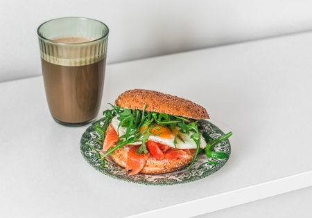 Delicious breakfast - coffee and egg, avocado, salmon, arugula burger on a light backgroundの写真素材