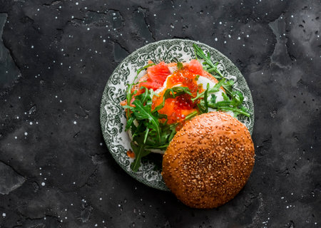 Breakfast, tapas, snack burger with egg, salmon, arugula and red caviar on a dark background, top viewの写真素材