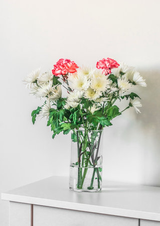 Bouquet of chrysanthemums in a glass vase on a white tableの写真素材