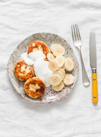 Cottage cheese syrnyky with greek yogurt and banana on a light background, top viewの写真素材