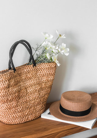 A wicker straw summer bag, a hat and a magazine on a wooden bench. summer seasonの写真素材