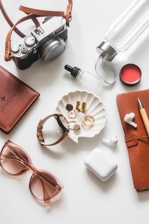 Women's travel accessories - camera, sunglasses, jewelry, notepad, passport, water bottle, lip balm on a white background, top viewの写真素材