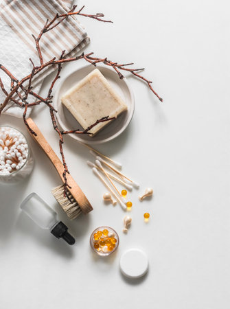 Accessories for morning hygiene - natural soap, serum, vitamins, cotton swabs, towel on a light background, top viewの写真素材