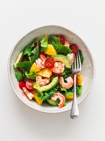 Delicious avocado, mango, shrimp, tomato salad on a ligth background, top viewの写真素材