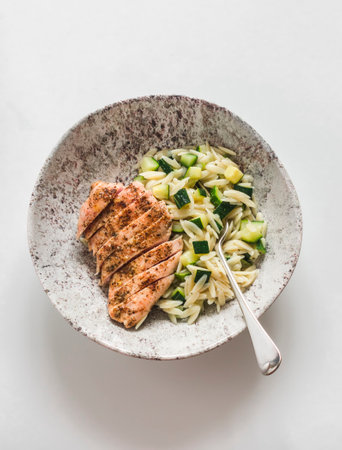 Grilled chicken breast and orzo with zucchini - a delicious lunch on a light background, top viewの写真素材