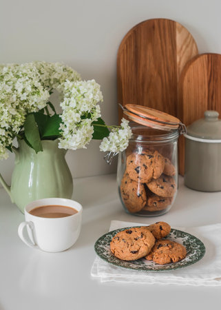 Coffee, cookies with chocolate drops on the kitchen table with a bouquet of hydrangeasの写真素材