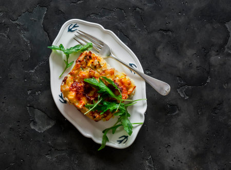 Delicious tapas - a piece of zucchini frit potatoes with arugula salad on a dark background, top viewの写真素材