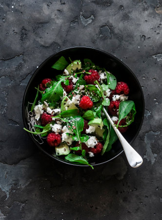 Ricotta, avocado, raspberry, arugula salad on a dark background, top viewの写真素材