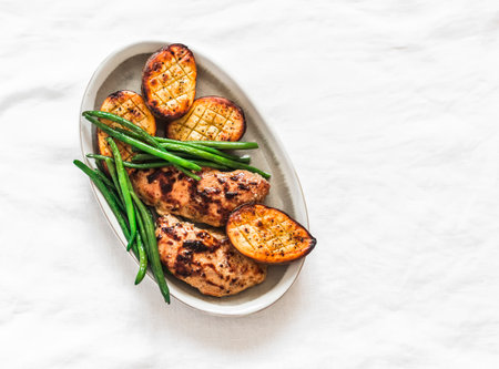 Grilled lunch - turkey fillet, potatoes, green beans on a light background, top viewの写真素材