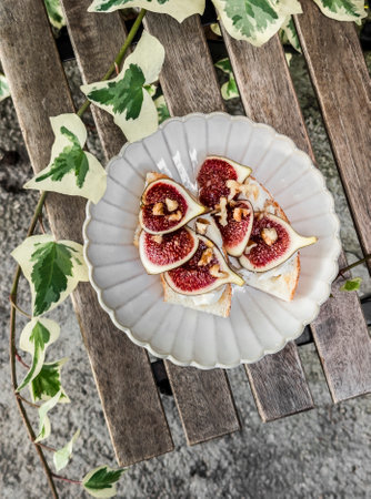 Bruschetta with cream cheese, figs, nuts and honey on a wooden table, top view