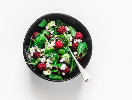Ricotta, avocado, raspberry, arugula salad on a light background, top viewの写真素材