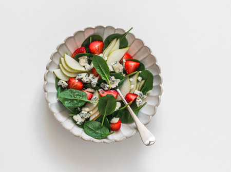 Pear, spinach, gorgonzola cheese, strawberry salad on a light background, top viewの写真素材