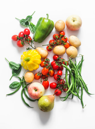 A variety of seasonal vegetables and fruits on a white background - cherry tomatoes, potatoes, string beans, squash, pear, appleの写真素材
