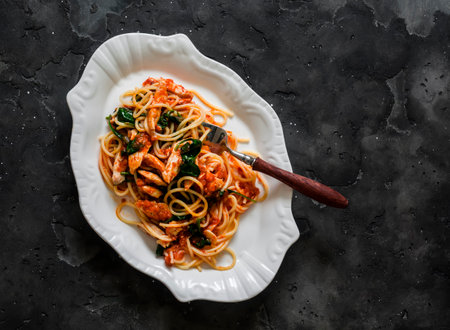 Spaghetti with tomato sauce, chicken fillet and spinach on a dark background, top viewの写真素材